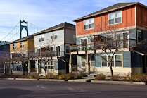 Small multi-unit buildings in the Saint Johns neighborhood of Portland, with a view of the St Johns Bridge in the background